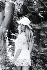 Young woman holding hands while standing on tree trunk