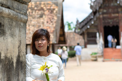 Portrait of woman standing by flowering plants
