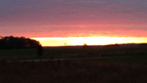 Scenic view of silhouette field against sky at sunset