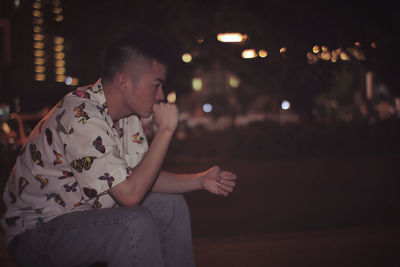 Midsection of man looking away while sitting at night