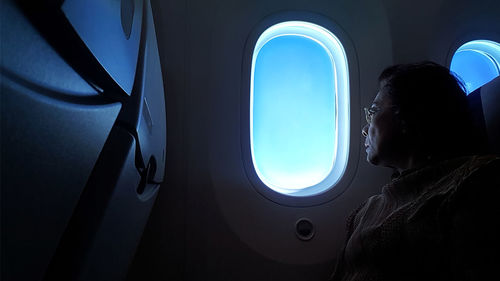 Woman looking through window while sitting in airplane