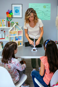 High angle view of woman using digital tablet while sitting on table