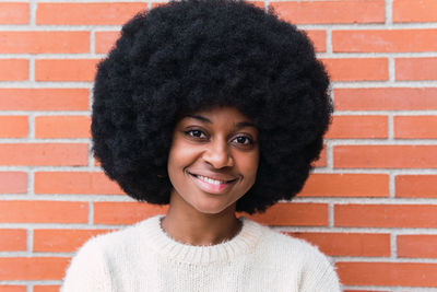 Portrait of young woman against brick wall