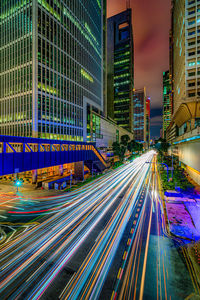 Light trails on road amidst buildings in city at night