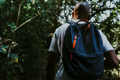 Rear view of man walking in forest with a backpack 