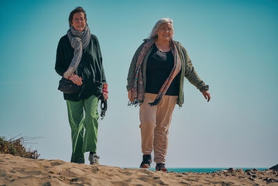 Two woman they walk on the beach on a sunny day