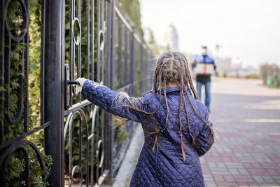 Rear view of girl standing by railing against sky