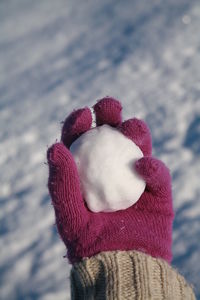 Close-up of human hand with snow against the sky