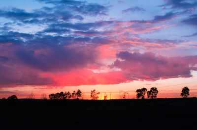Silhouette landscape against dramatic sky during sunset