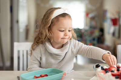 Cute girl eating food while sitting at home