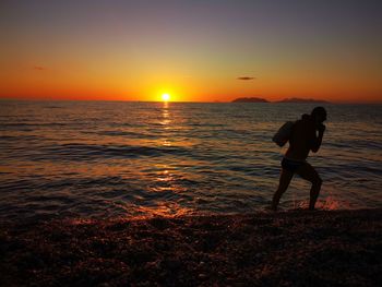 Man standing on beach against sky during sunset