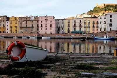 Boats moored in canal by buildings against sky in city