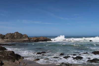 Scenic view of rocks in sea against blue sky