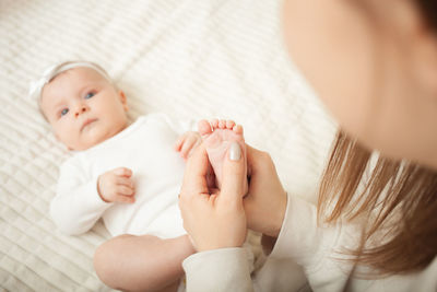 Mother massages her little daughter, newborn baby. lies on bed in bedroom, 