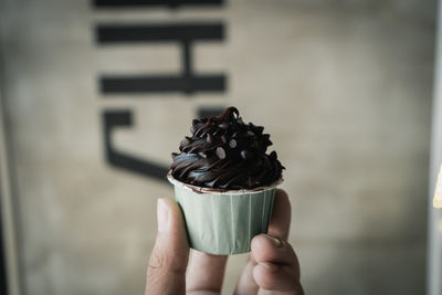 Close-up of hand holding chocolate cupcake