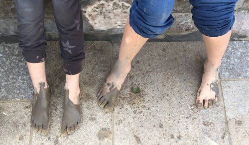 Low section of people with muddy feet by wall