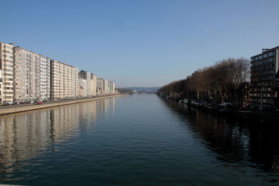 River amidst buildings in city against clear sky
