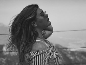 Portrait of young woman looking away against sky