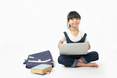 Smiling young woman using laptop on white background
