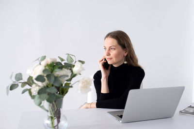 Young woman using laptop while sitting on table