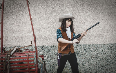 Portrait of young woman standing against wall