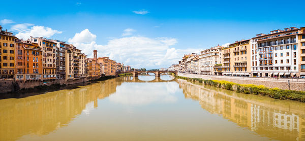 Bridge over canal amidst buildings against sky in city of florence with ponte vecchio 