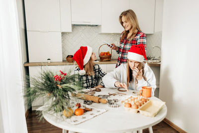 Mom and her daughters cook christmas cookies or gingerbread together, family cooking of festive food