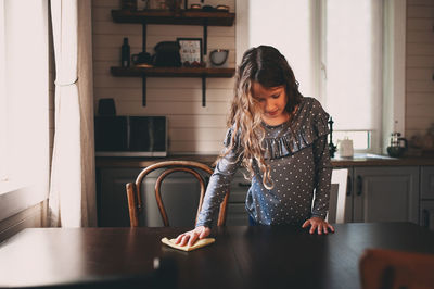 Girl cleaning table at home