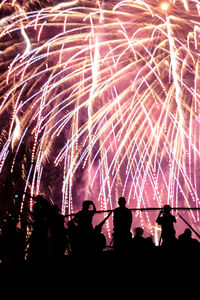 Silhouette people watching firework display at night