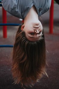 Portrait of woman hanging upside down in playground