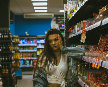 Thoughtful young woman standing by shelf in store