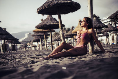 Woman in bikini sitting at beach