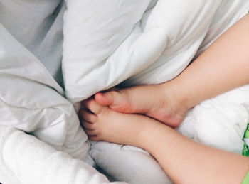 Low section of child sleeping on bed