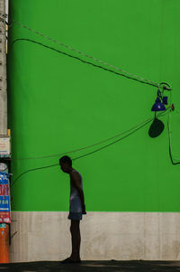 Rear view of boy standing against wall