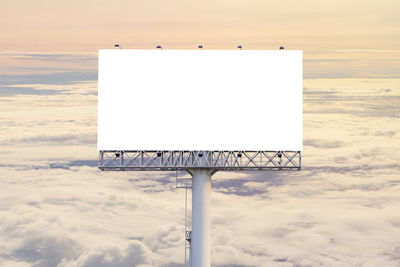 Sign board on sea against sky