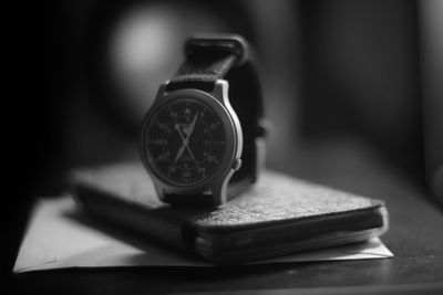 Close-up of wristwatch with mobile phone on table