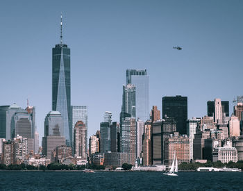 One world trade center with modern buildings in city against clear sky