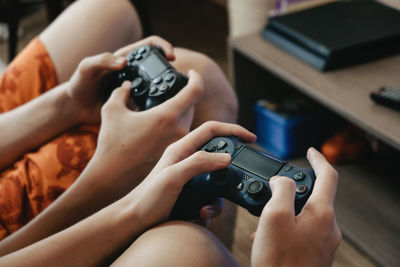 Midsection of boys playing video game at home