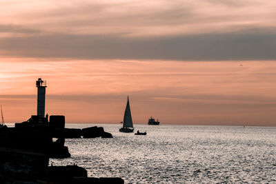 Silhouette sailboats in sea against sky during sunset