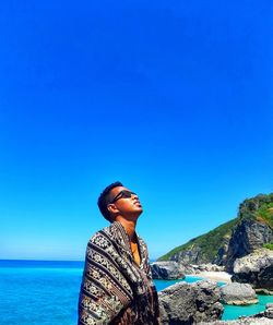 Man standing by sea against clear blue sky