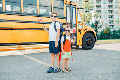 Full length of boys standing by bus