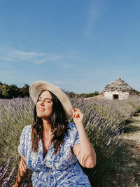 Portrait of beautiful happy young woman sitting in lavender field