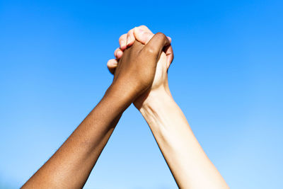 Low angle view of holding hands against sky