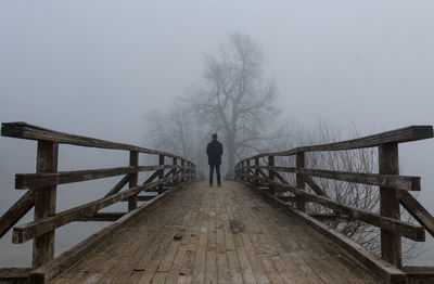 Rear view of man standing on footbridge