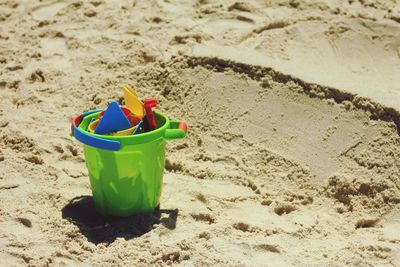 High angle view of bucket with toys on sand at beach