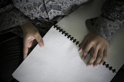 Midsection of blind person reading bible in braille