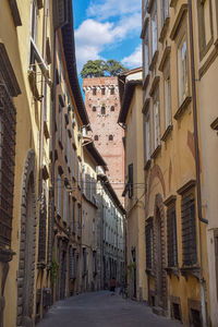 Narrow street amidst buildings in town leading to the guinigi tower