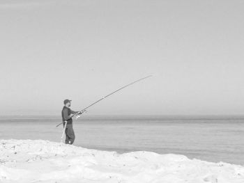 Man fishing in sea against sky