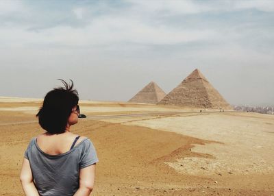 Rear view of woman standing in desert against sky