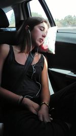 Young woman using mobile phone while sitting in car